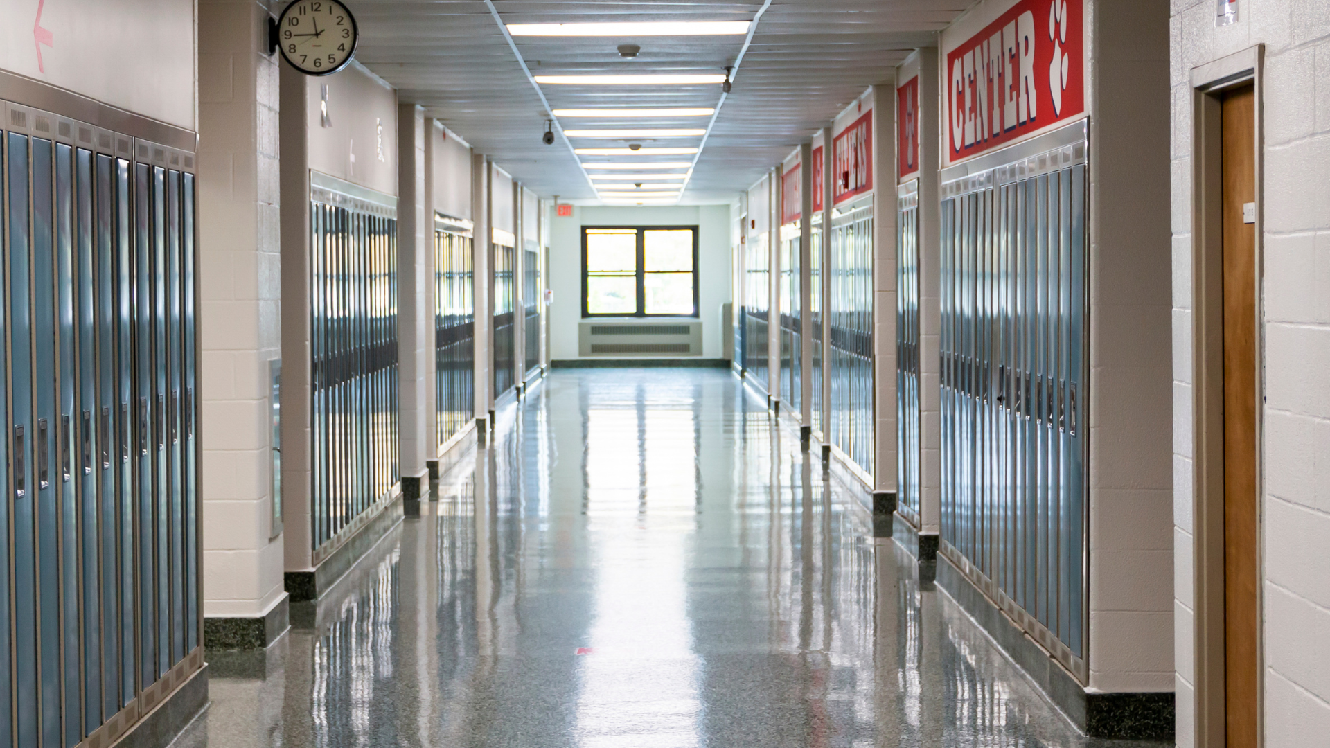 An empty school hallway with lockers and a clock on the wall.