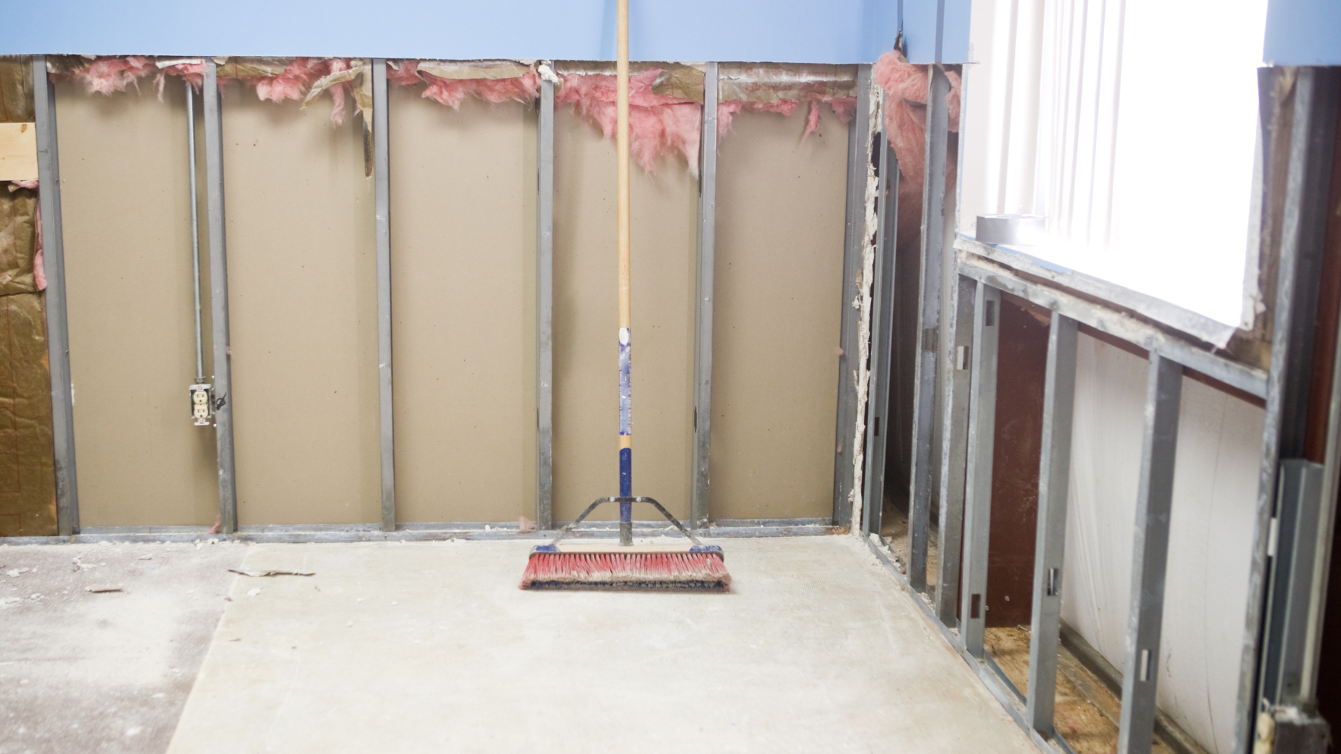 A mop is sitting on the floor in a room under construction.