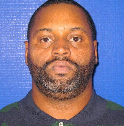 A man with a beard is wearing a blue and green shirt