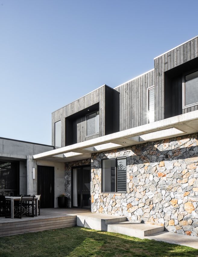 Modern home exterior with stone and wood siding, deck, and green lawn under a blue sky — Make The Mark Building Services in Illawarra, NSW