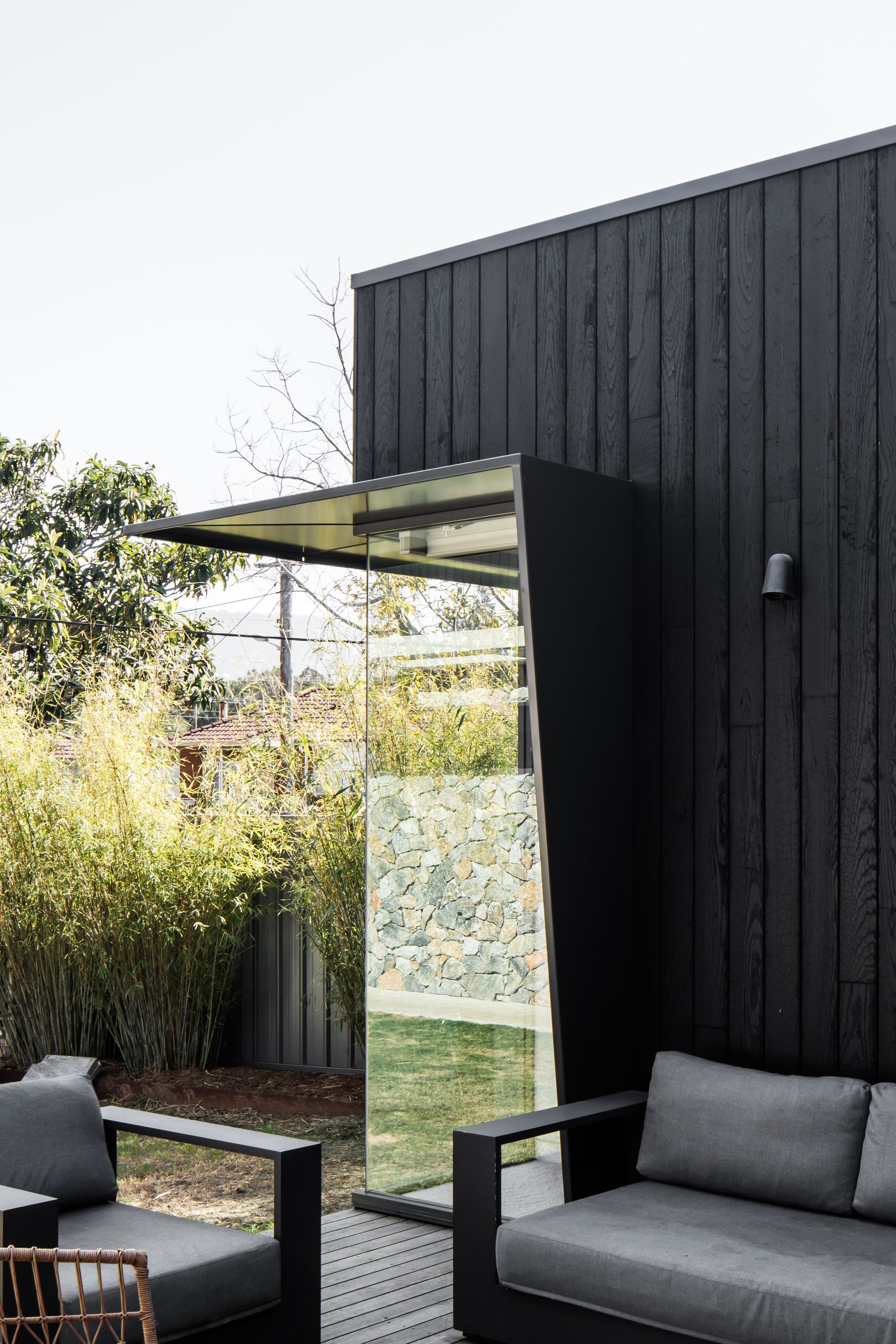 Black exterior building with mirrored panel; outdoor seating area — Make The Mark Building Services in Mangerton, NSW