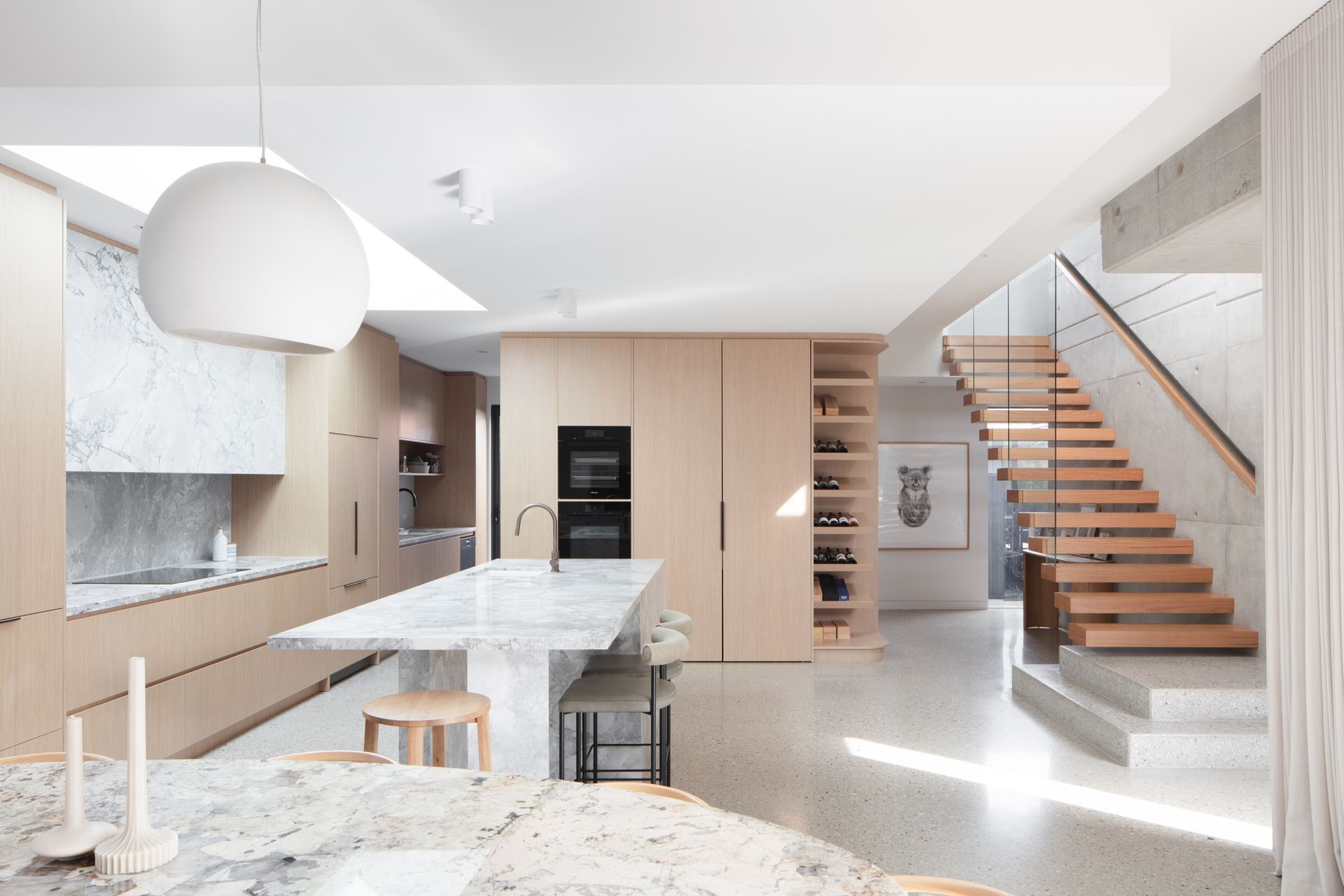 Modern kitchen with light wood cabinetry, marble countertops, and a wooden staircase — Make The Mark Building Services in Mangerton, NSW