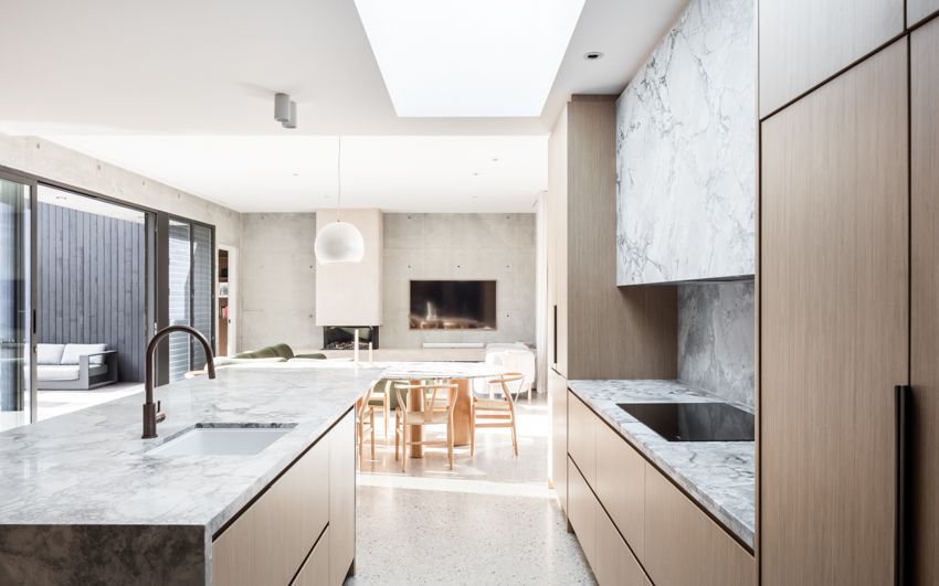 Modern kitchen with marble countertops, light wood cabinets, and a long skylight — Make The Mark Building Services in Illawarra, NSW