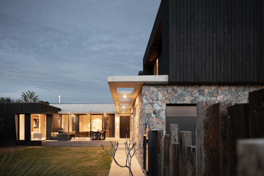Modern house exterior with stone and black wood siding at dusk — Make The Mark Building Services in Illawarra, NSW