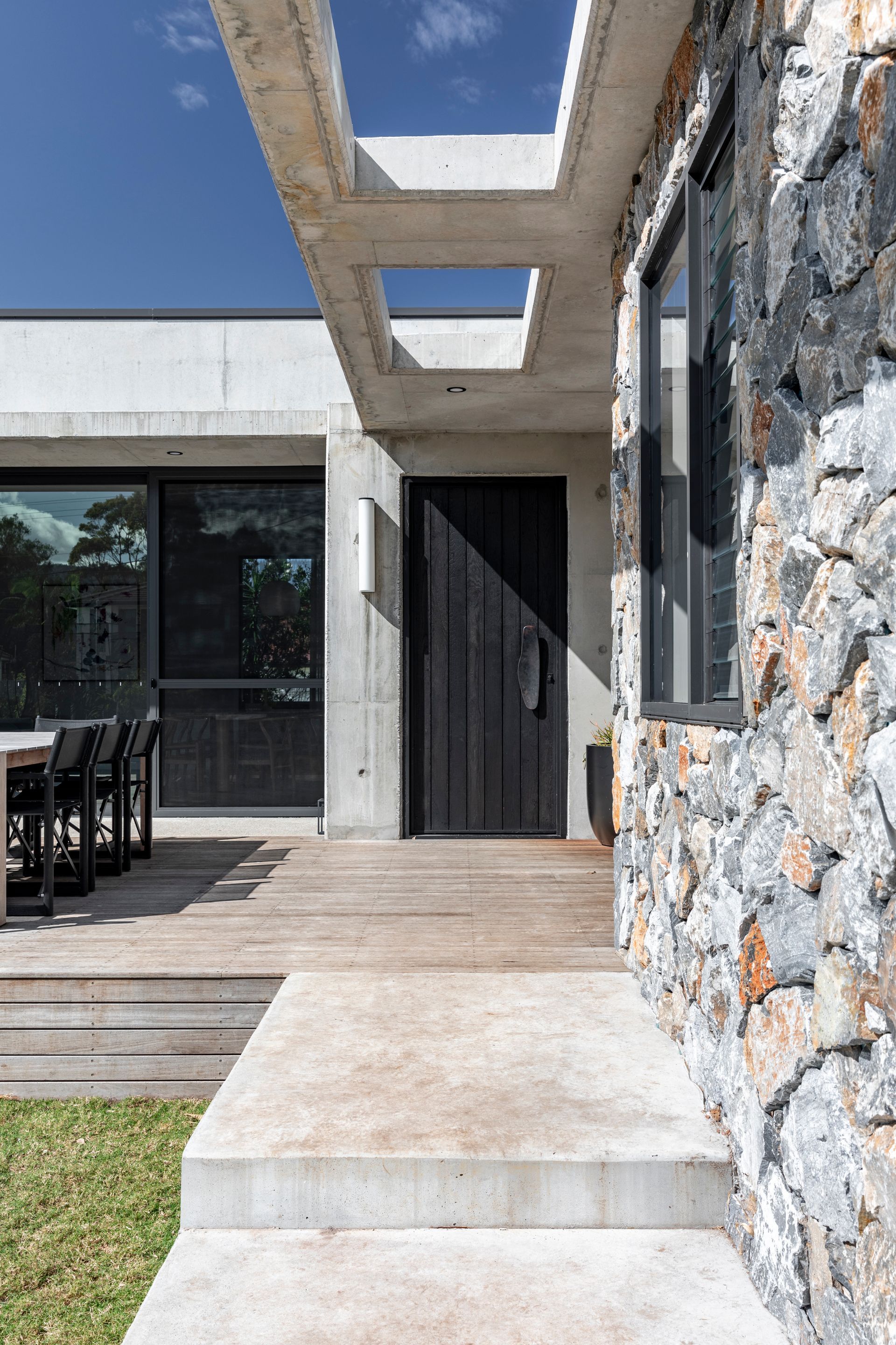 Stone facade, concrete porch, and wooden door under a concrete overhang on a modern building — Make The Mark Building Services in Illawarra, NSW
