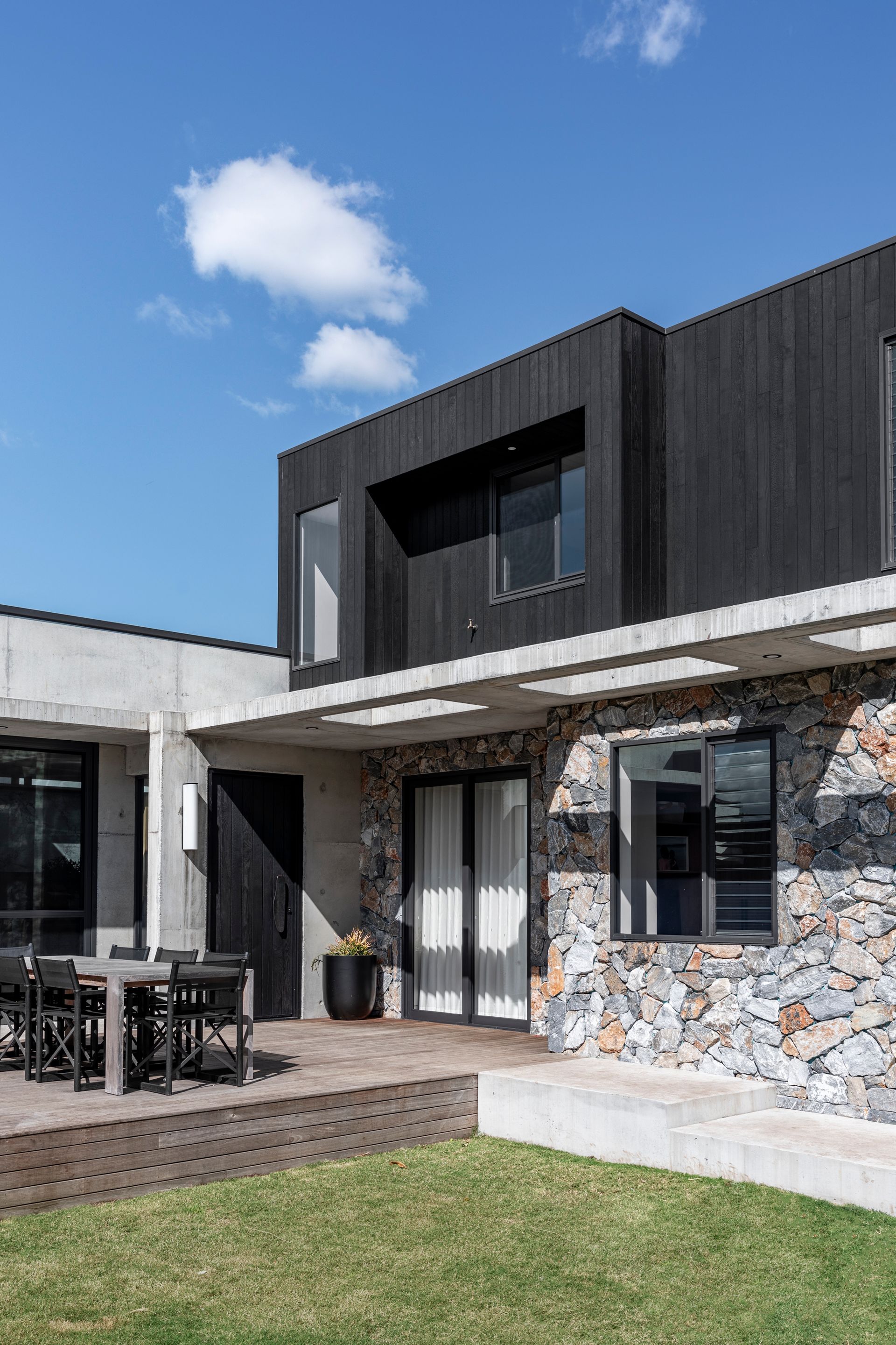 Outdoor patio with seating, open to a backyard. Glass doors reveal a kitchen — Make The Mark Building Services in Mangerton, NSW