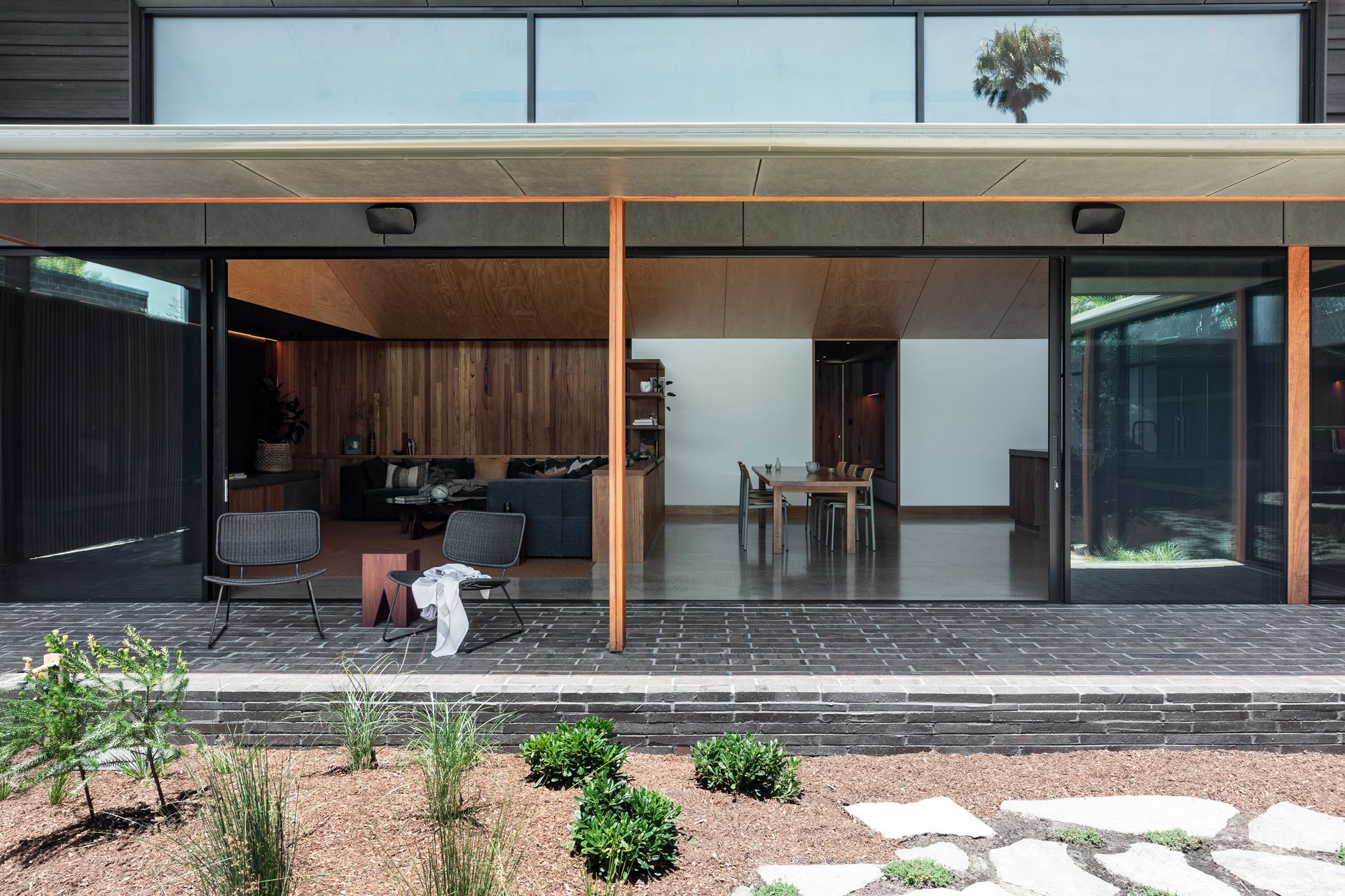 Modern home with open sliding glass doors, wooden interior, patio seating, and landscaped yard — Make The Mark Building Services in Illawarra, NSW