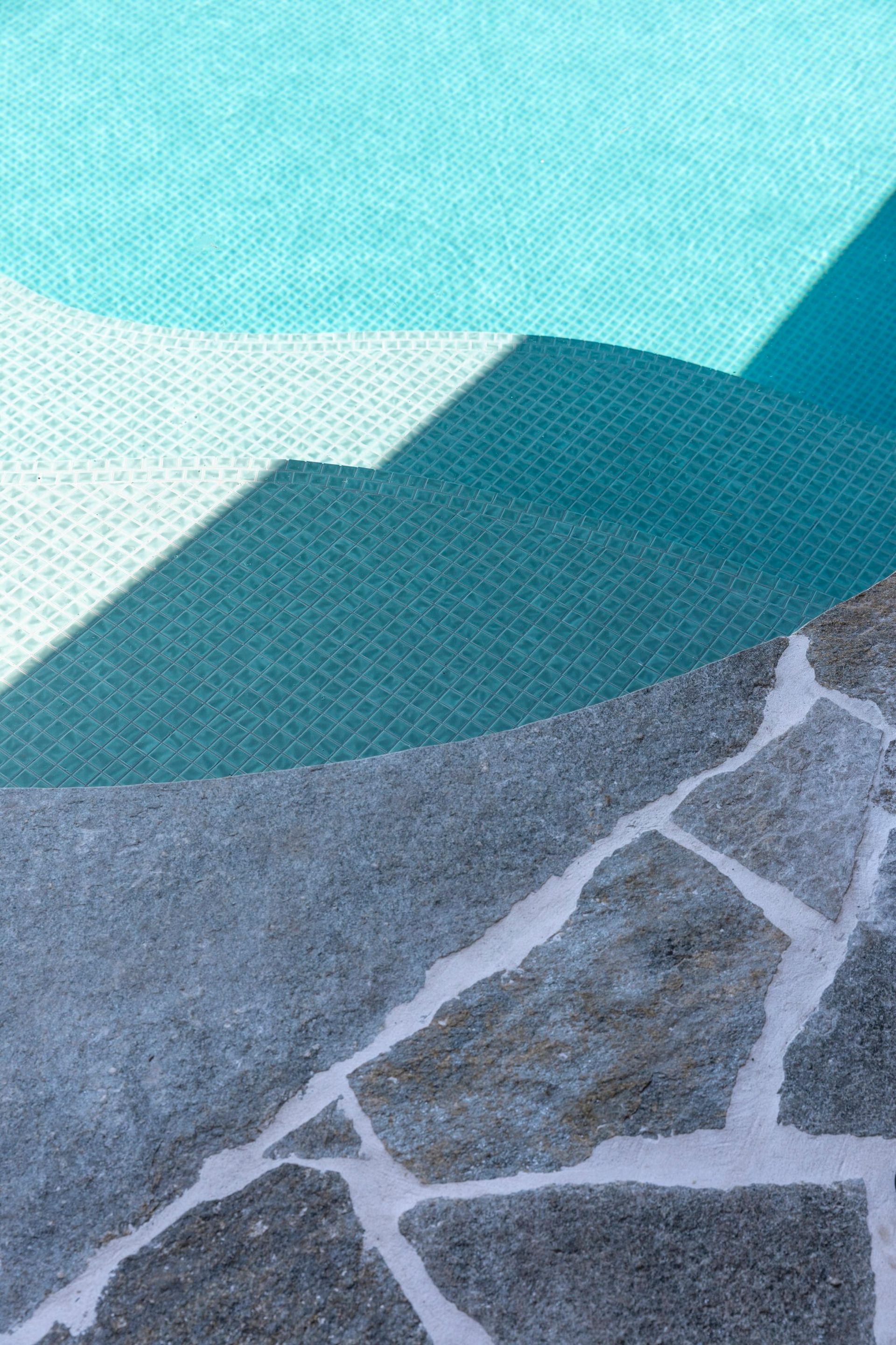 Stone patio and pool steps with turquoise water, creating abstract shapes in sunlight — Make The Mark Building Services in Illawarra, NSW
