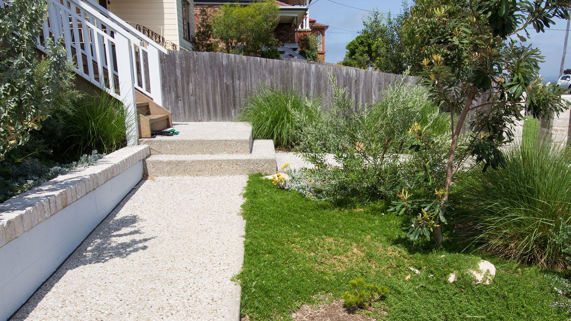 Concrete path and steps leading to a house with a wooden fence and garden — Make The Mark Building Services in Mangerton, NSW