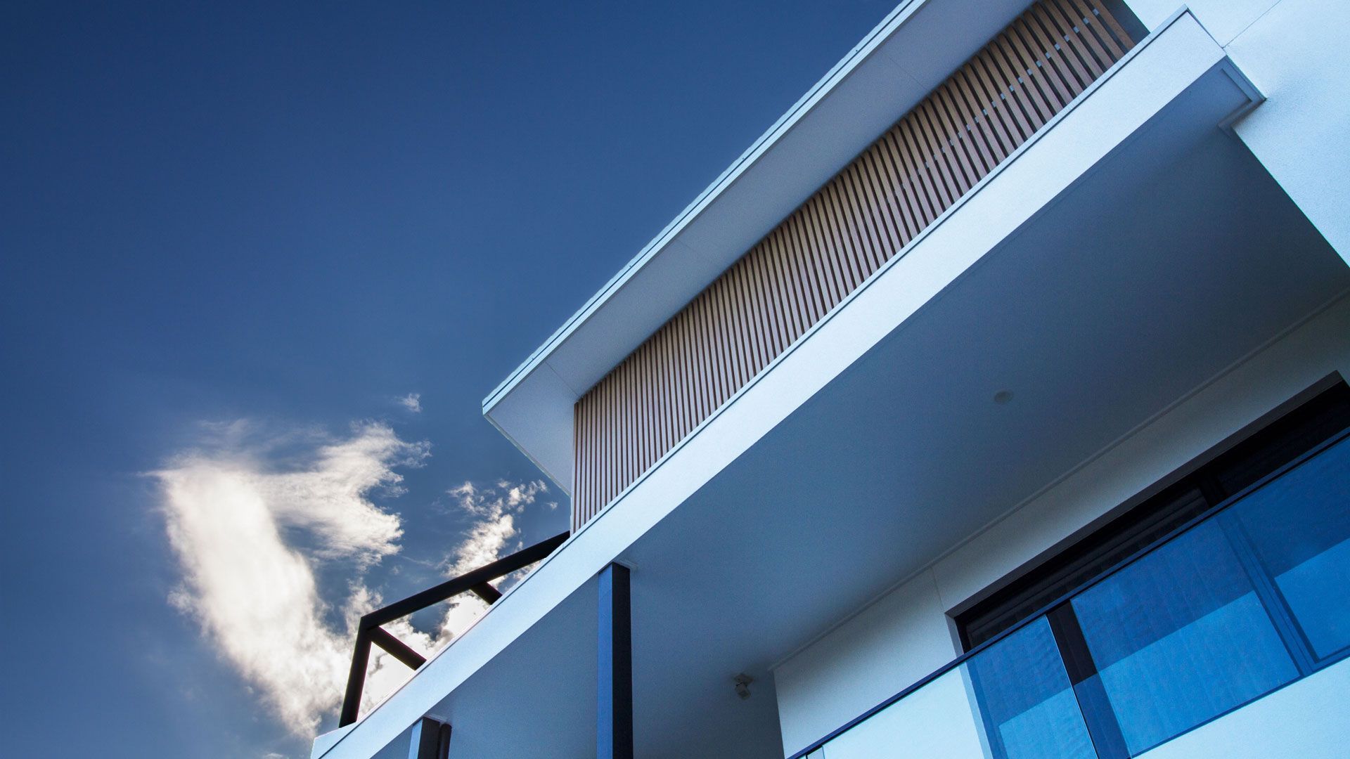 Modern white building with balcony against a bright blue sky  — Make The Mark Building Services in Illawarra, NSW