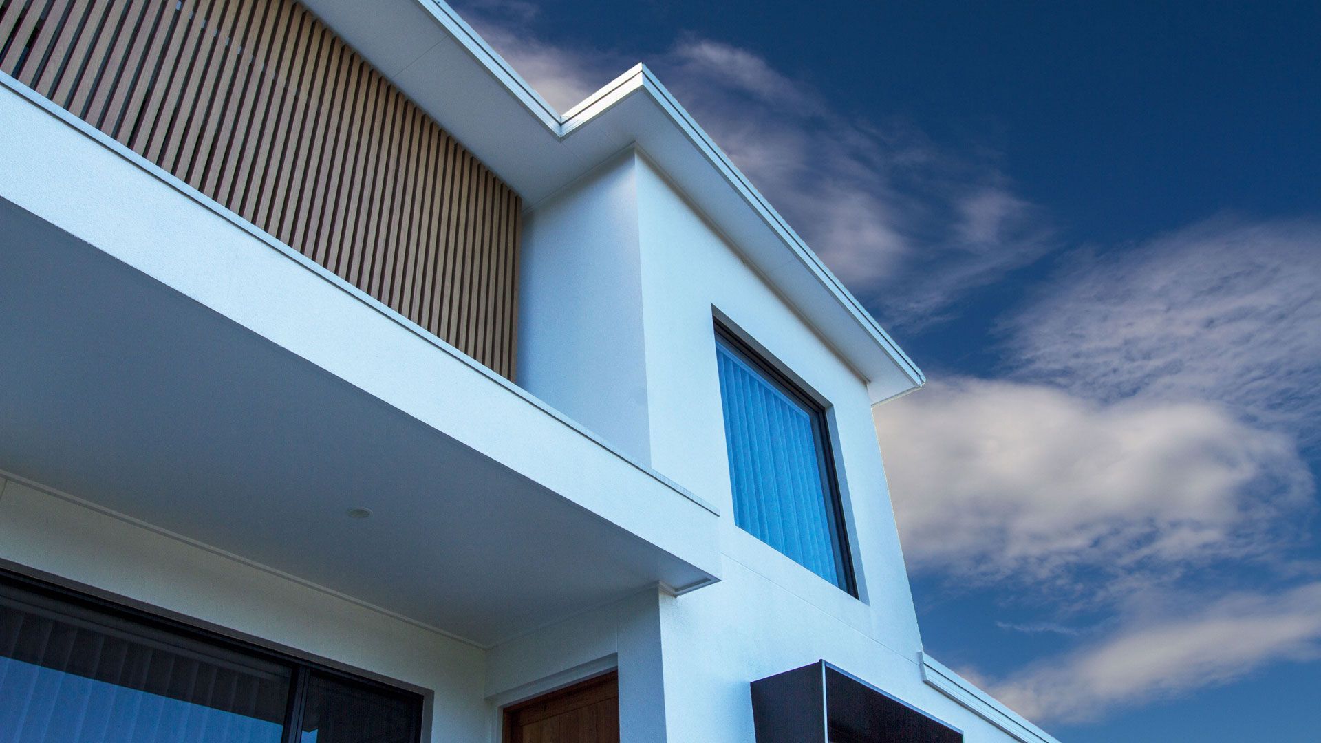 Modern white building with blue window, wooden paneling, and bright sky  — Make The Mark Building Services in Illawarra, NSW