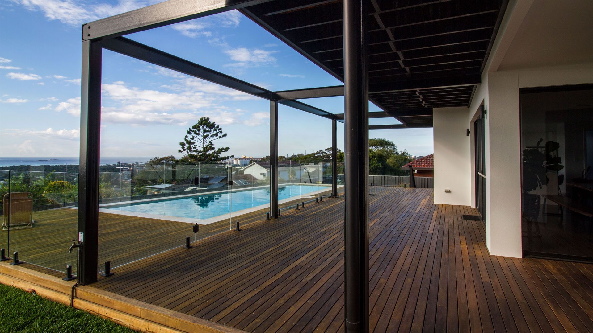 Wooden deck with pool, pergola, and house overlooking a scenic landscape  — Make The Mark Building Services in Illawarra, NSW