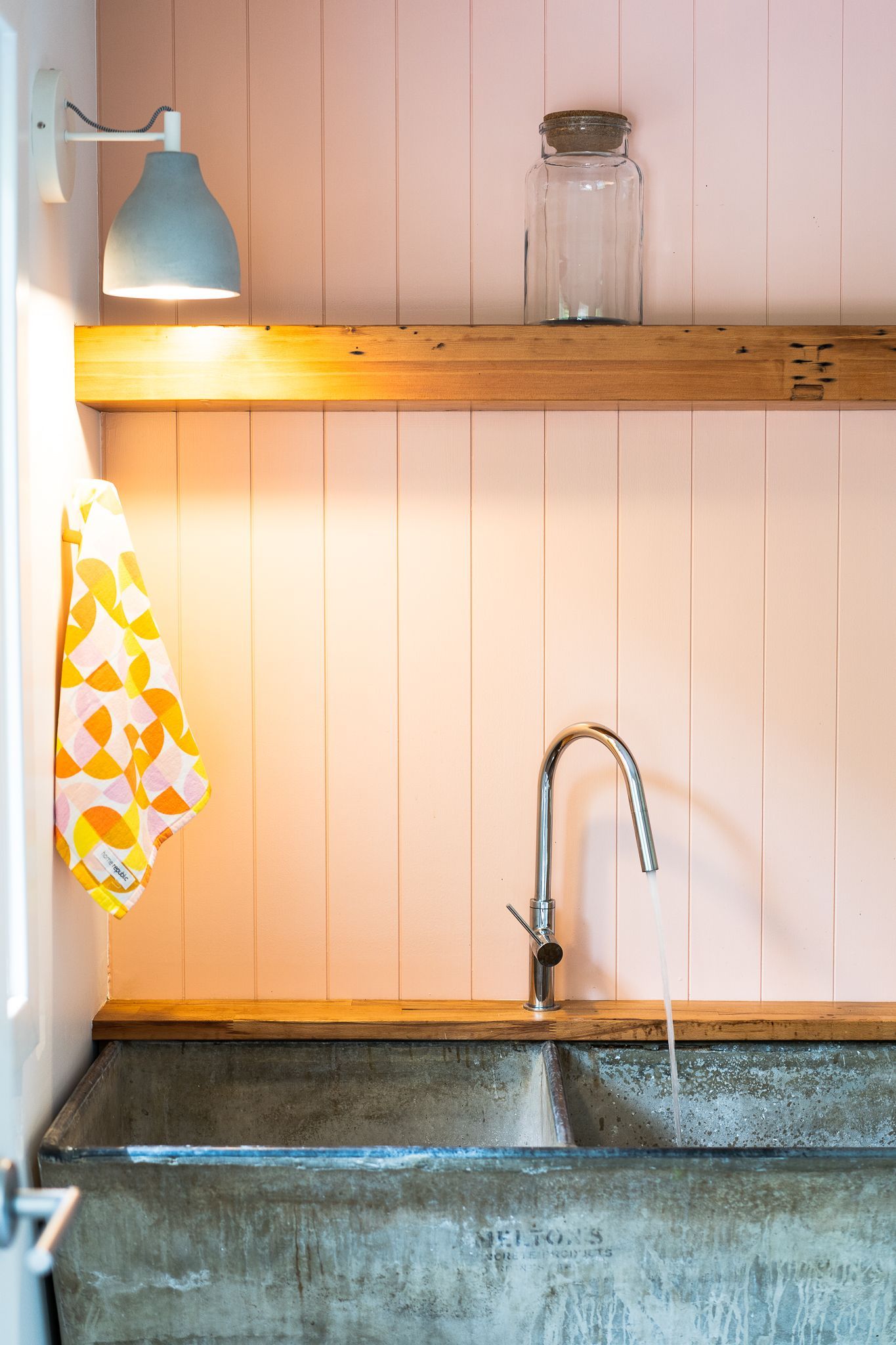 Concrete sink, chrome faucet, pink paneled wall, wooden shelf with jar, and gray lamp - Make The Mark Building Services in Mangerton, NSW