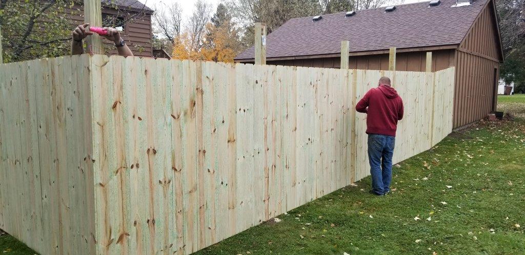Modern Fence — Man Standing Beside Wooden Fence in Deerwood, MN