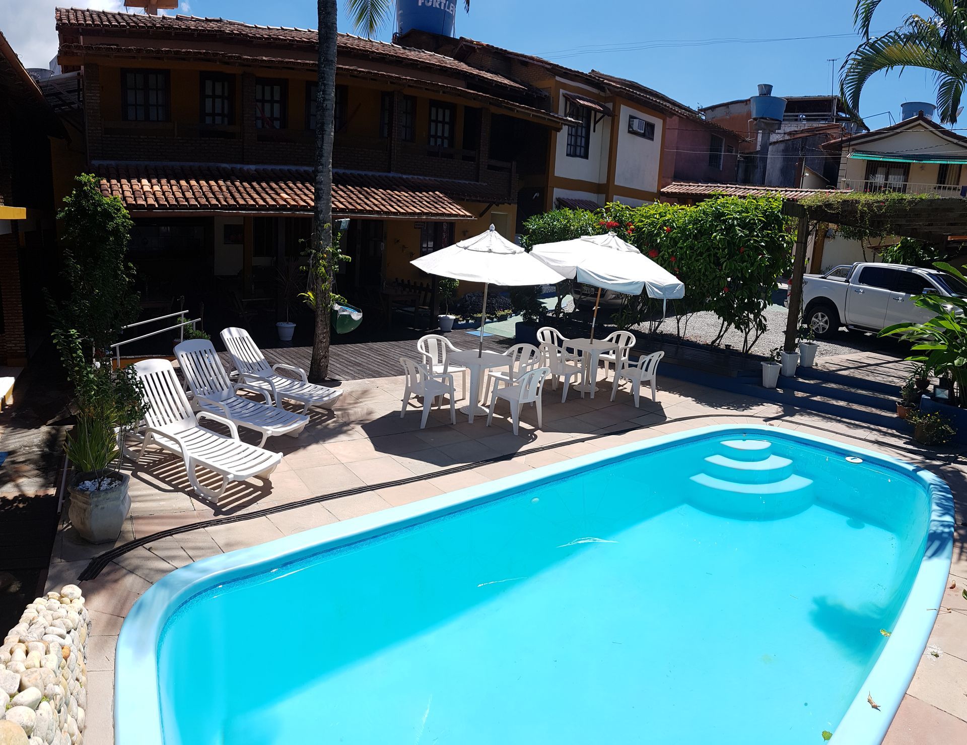 Uma grande piscina com cadeiras e guarda-sóis ao redor-Pousada-A-Flor-Da-Terra