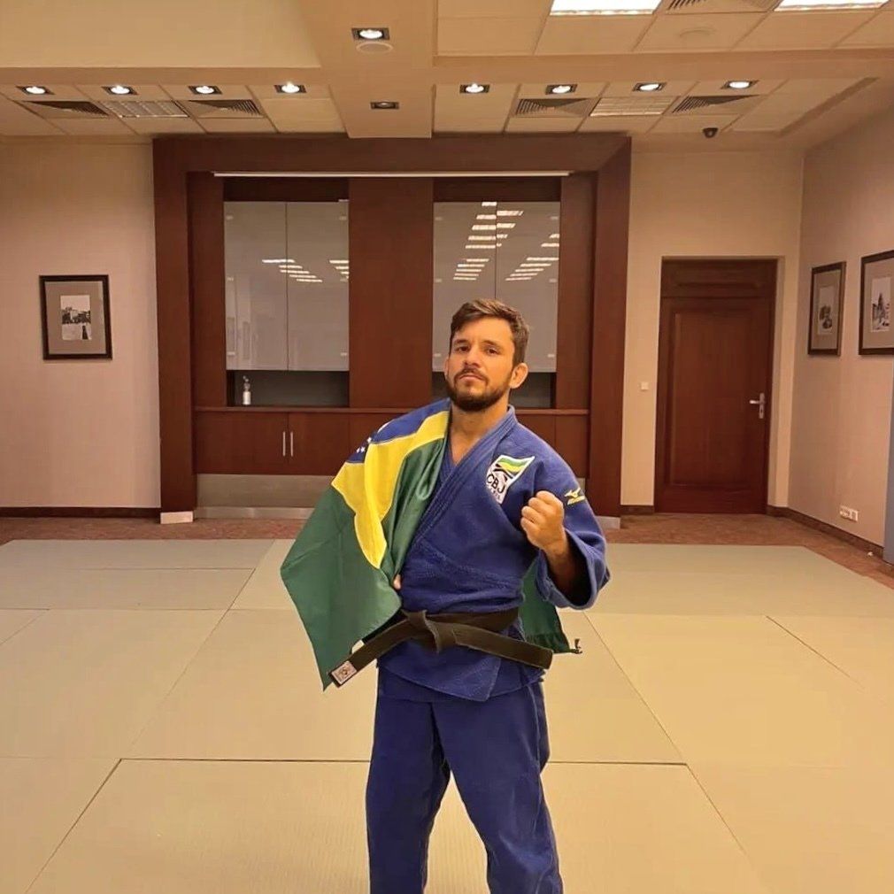 Felipe Queiroz, atleta do Instituto Ação e Reação, posicionado para foto com bandeira do Brasil