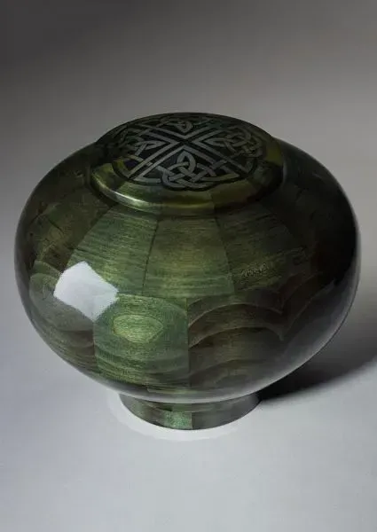 Dark green carved glass decorative bowl with a patterned lid on a white background