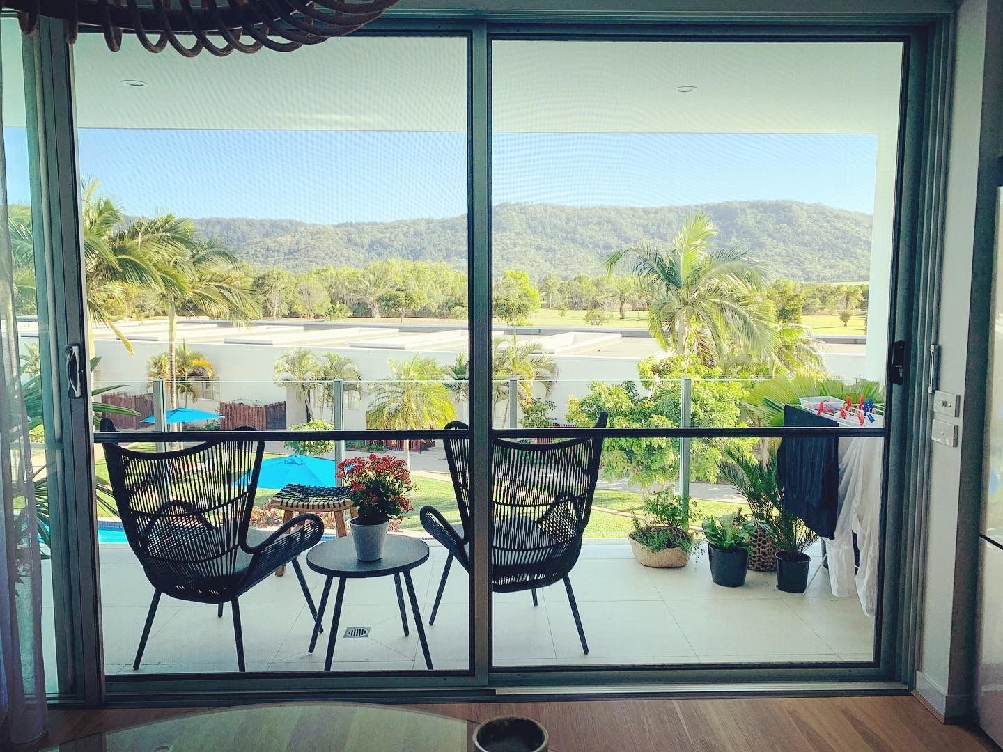 A living room with a sliding glass door leading to a balcony with chairs and a table.