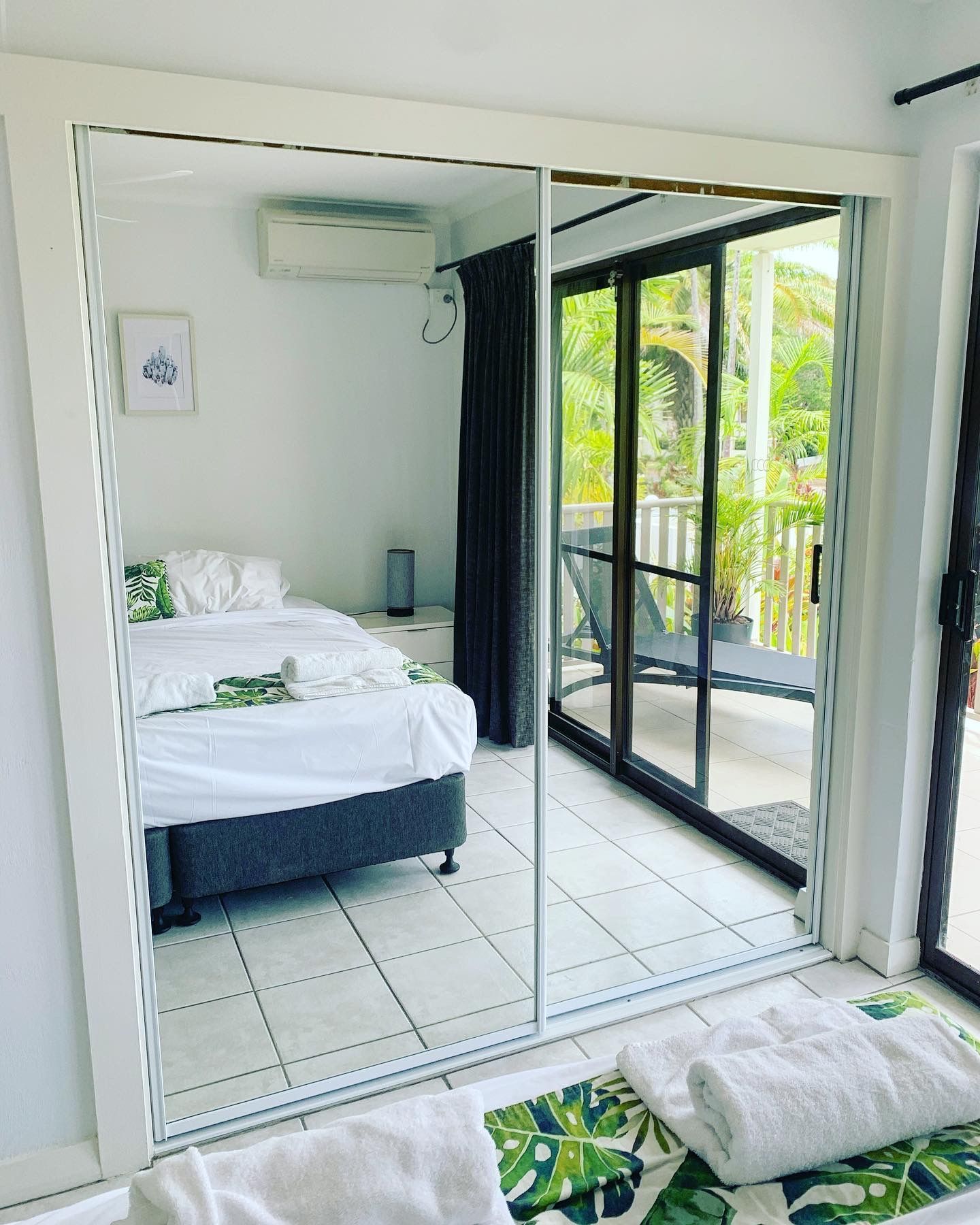 A bedroom with a large mirror and sliding glass doors leading to a balcony.