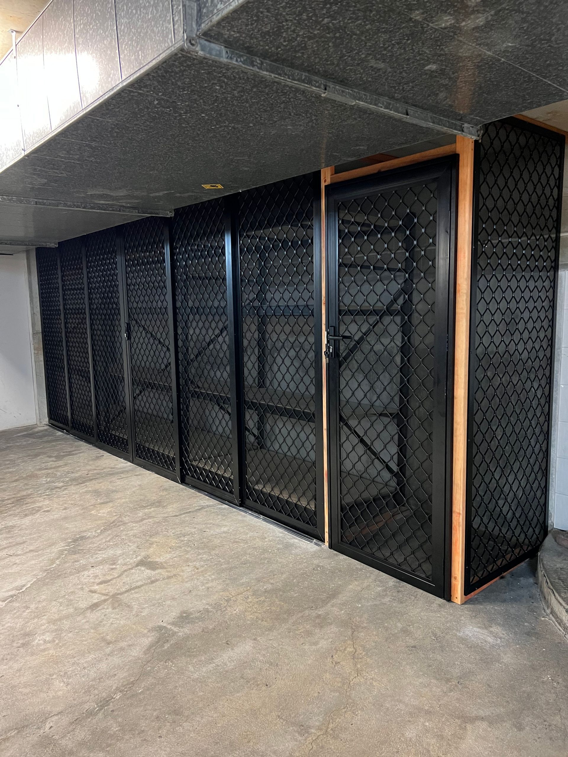 A row of black metal lockers are lined up in a room.