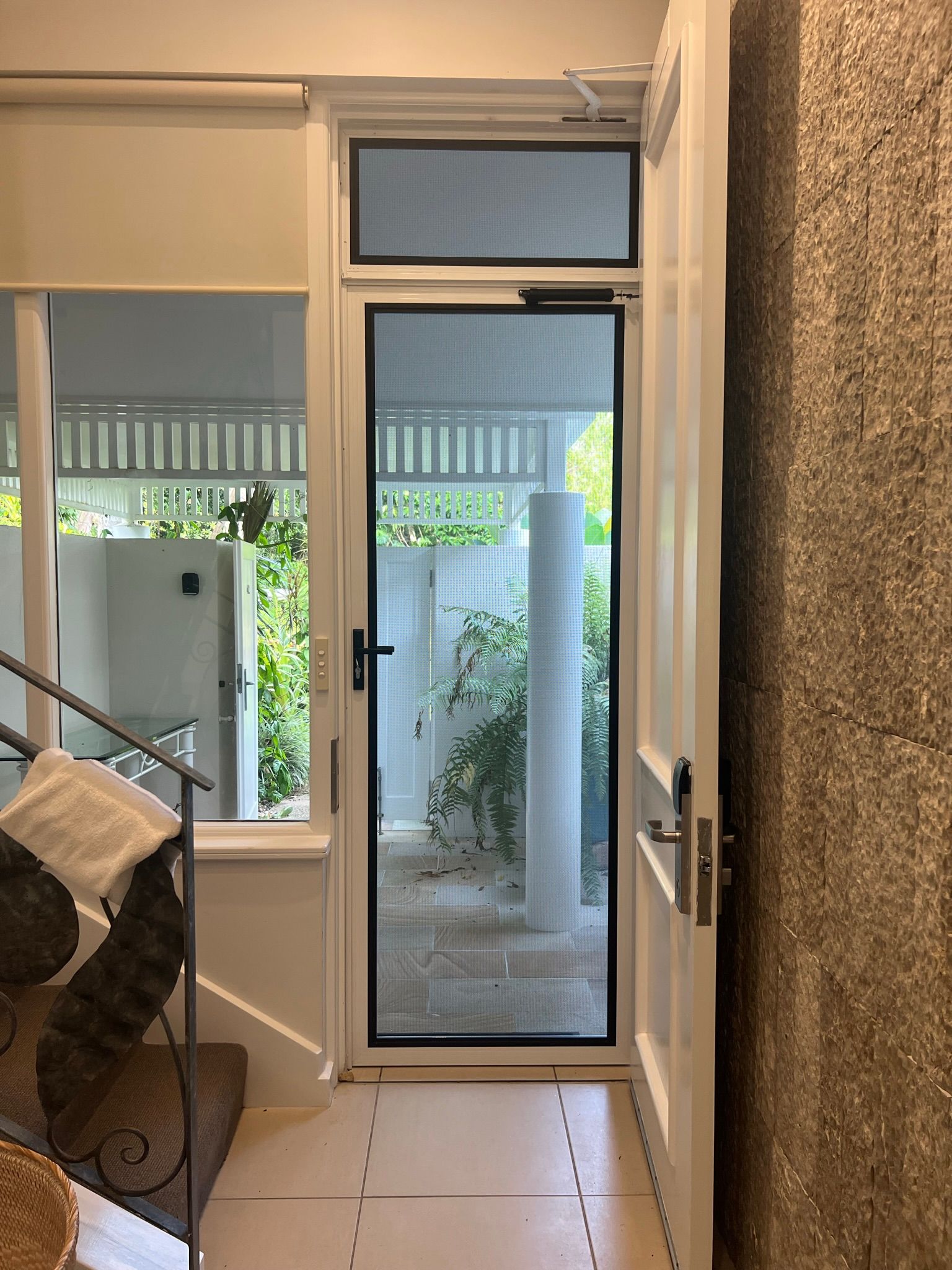 A hallway with stairs and a glass door leading to a porch.