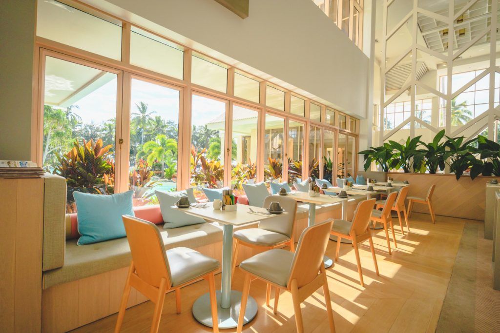 A restaurant with tables and chairs and lots of windows.