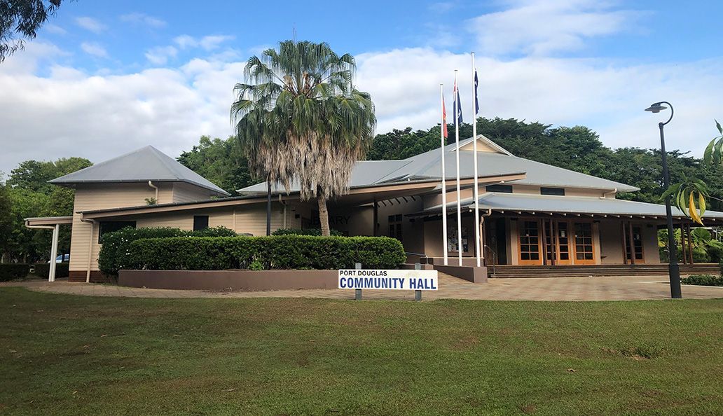 A large house with a gray roof is surrounded by trees and grass.