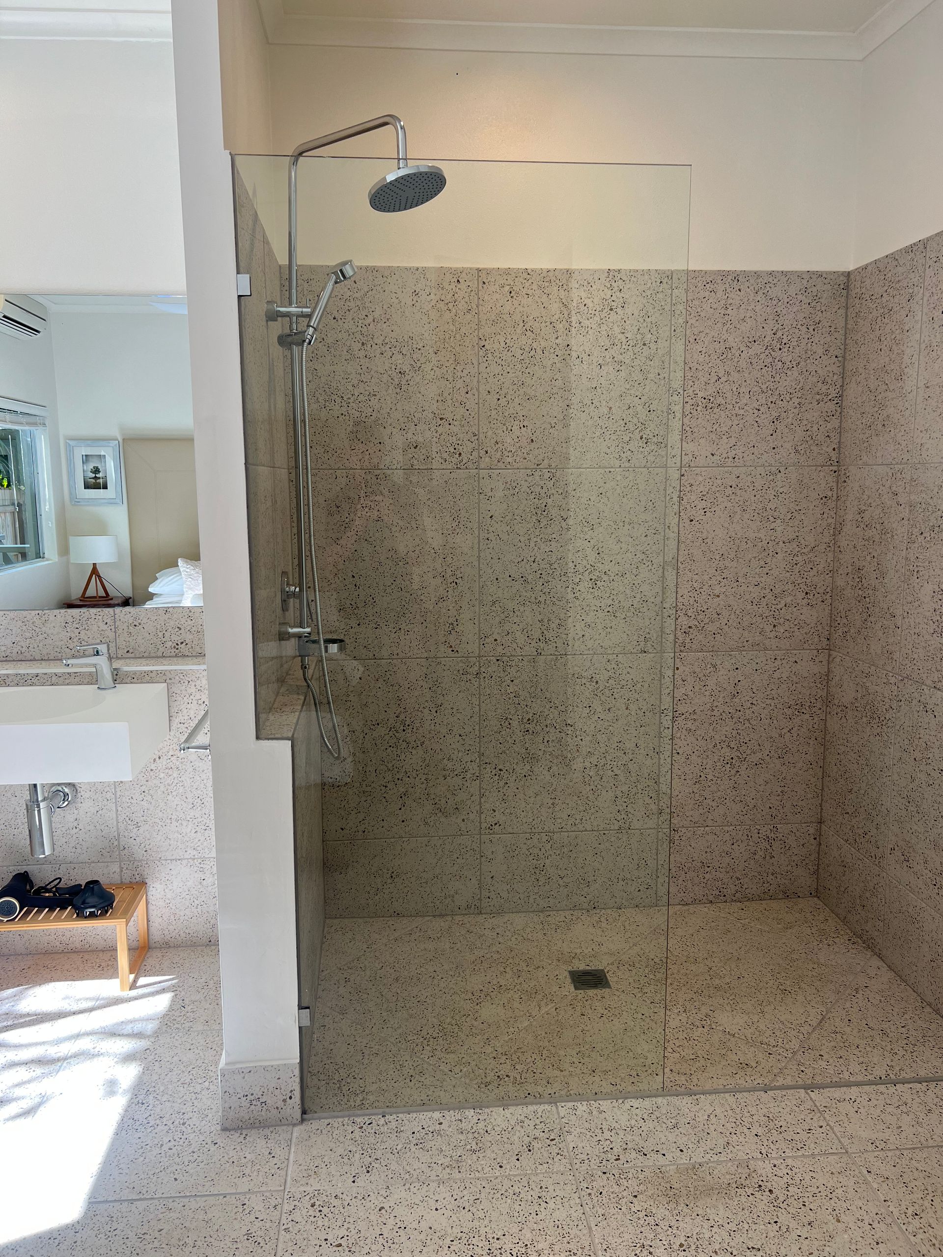 A bathroom with a walk in shower and a sink