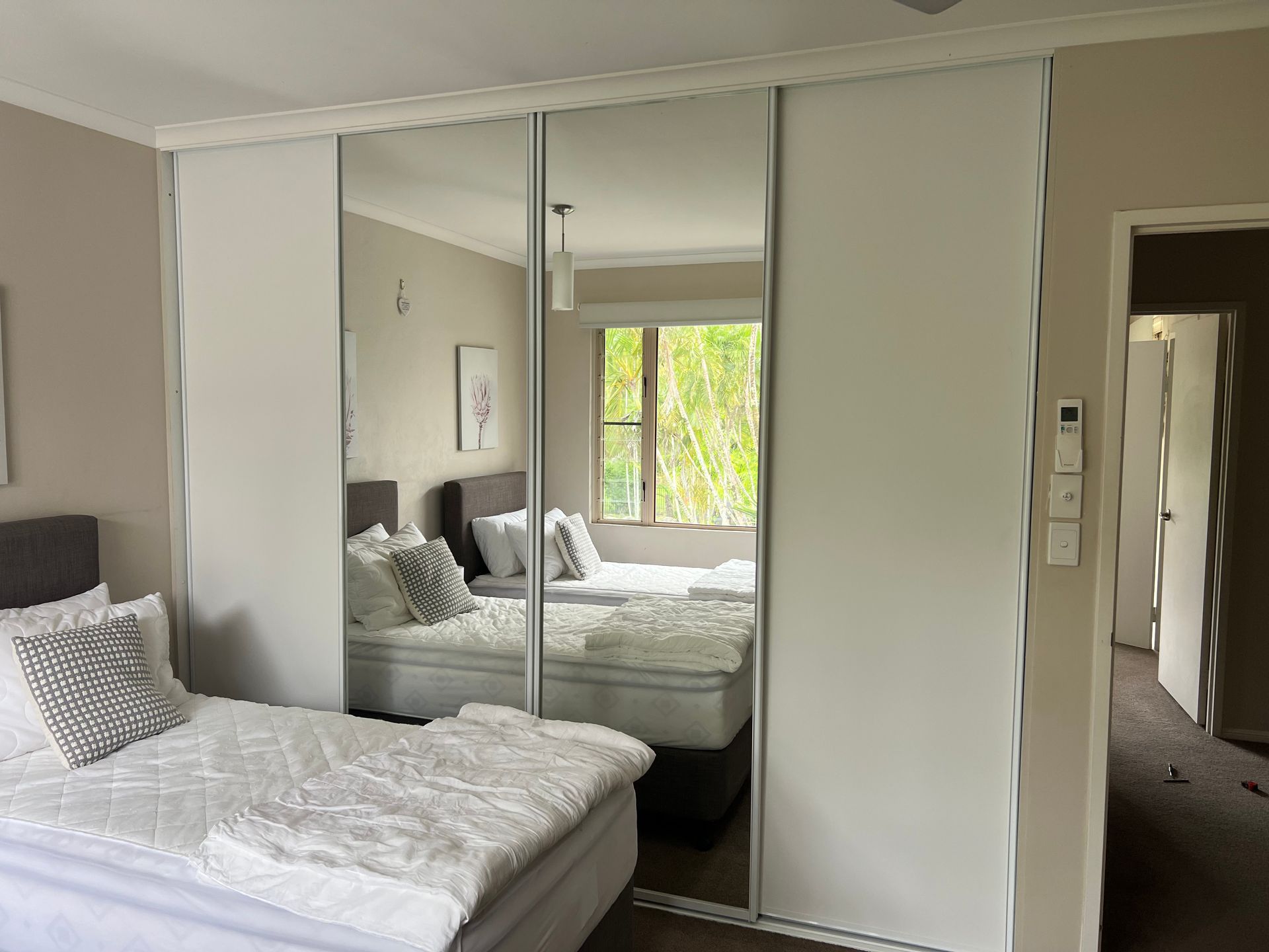 A bedroom with a bed and a mirrored wardrobe.