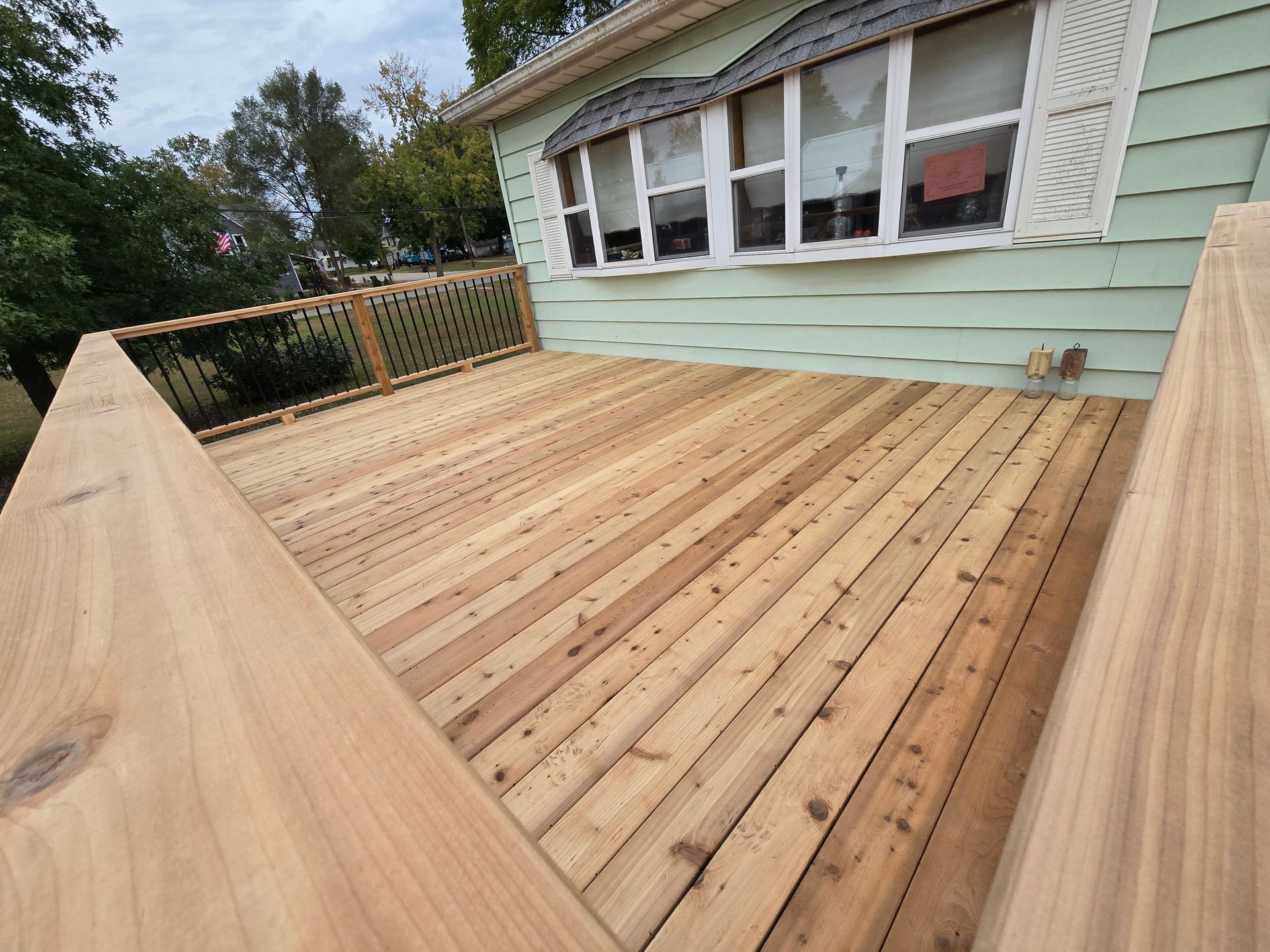 A wooden deck is sitting in front of a house.