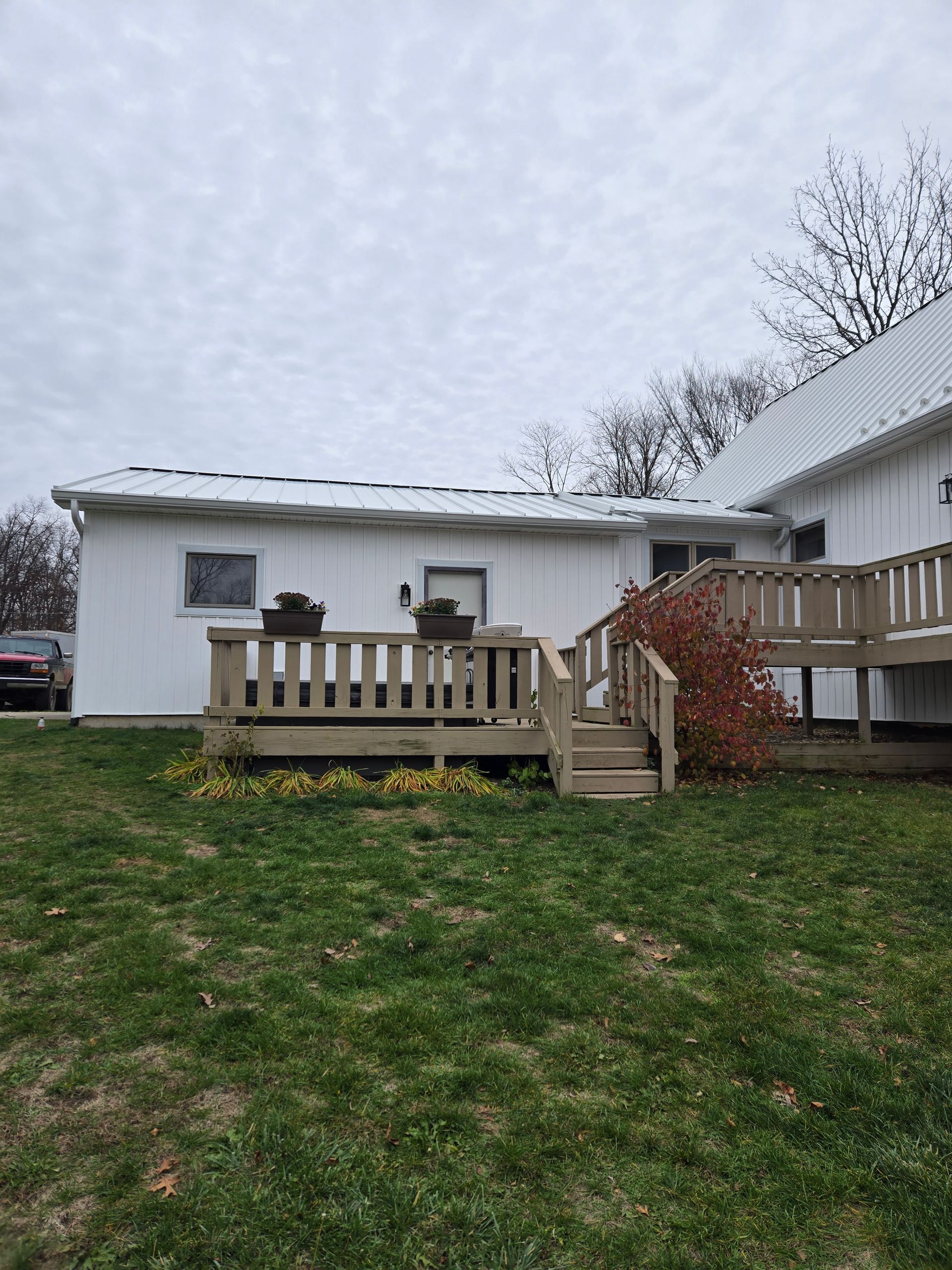 A white house with a deck and stairs in the backyard.