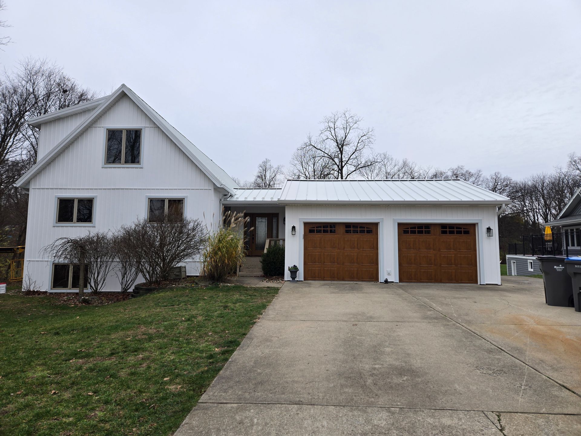 A white house with two garage doors and a driveway.
