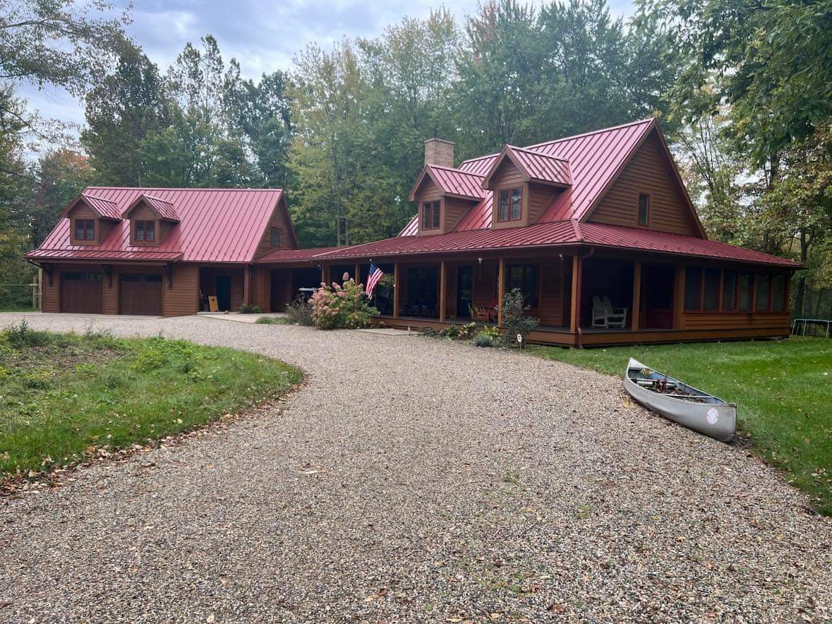 a large log cabin with a red roof and a canoe in front of it