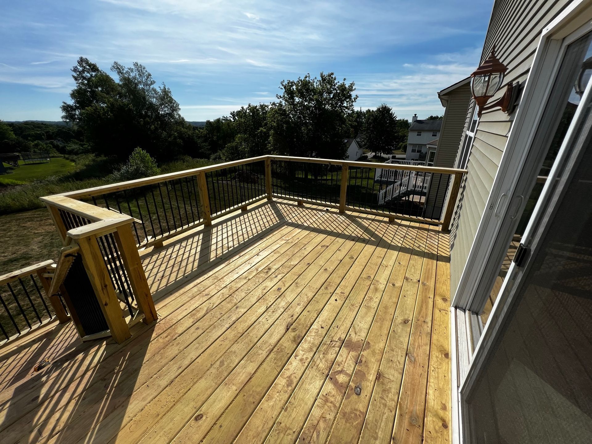 a wooden deck with a railing and a sliding glass door