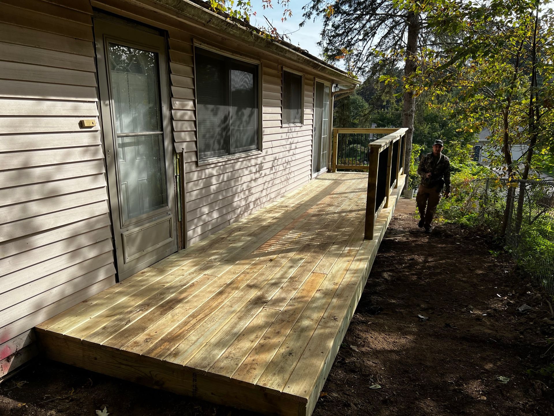 a man is standing on a wooden deck in front of a house .