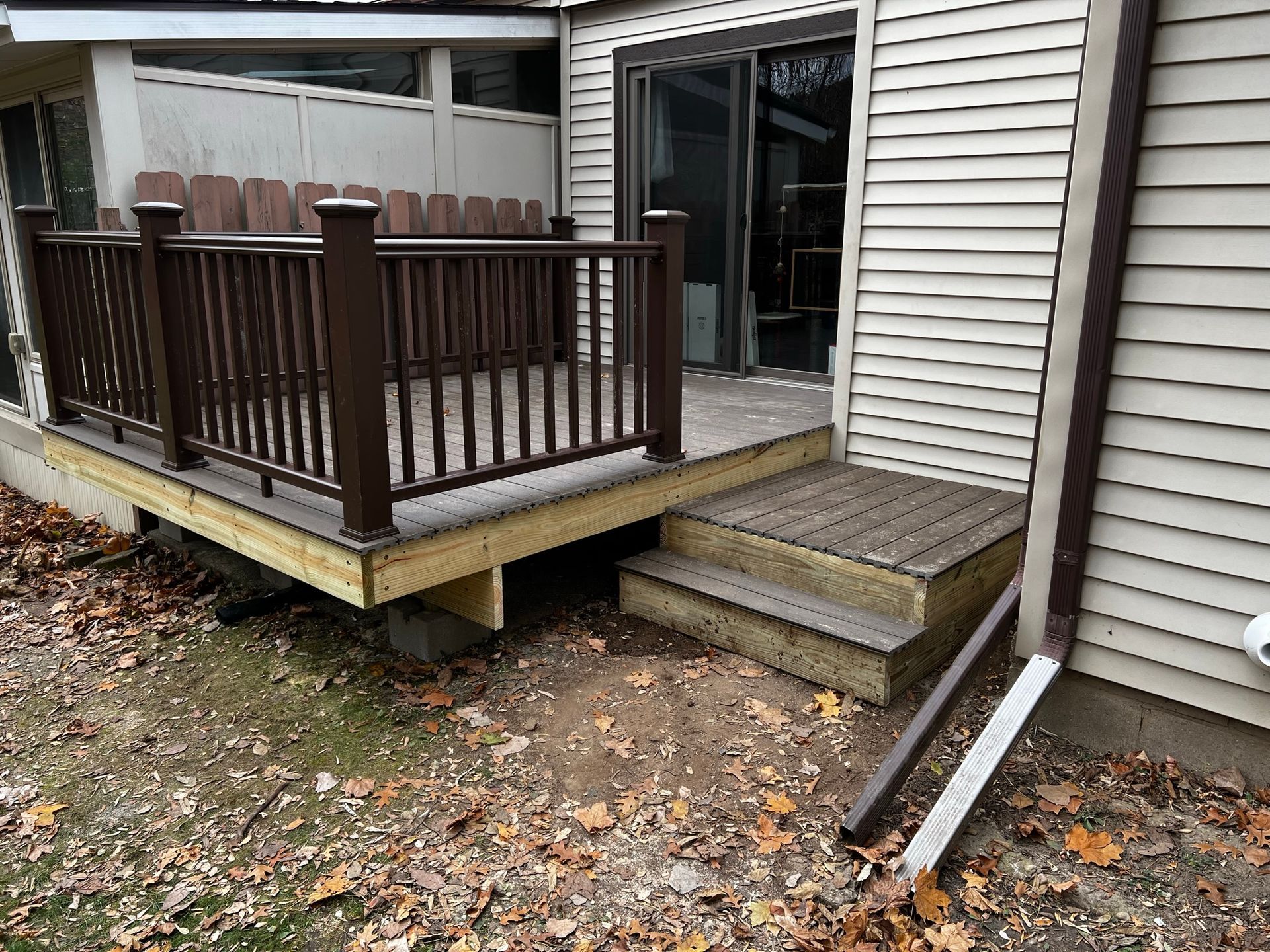 a wooden deck with stairs and a railing next to a house .