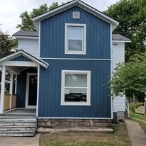 A blue and white house with a porch and stairs.