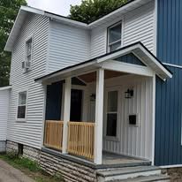 A white house with a blue siding and a porch.