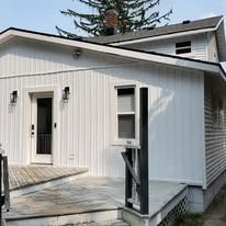 A white house with a gray roof and a porch.