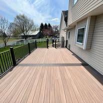 A wooden deck with a fence and stairs leading to it is in front of a house.