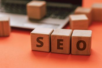 The word seo is written on wooden blocks in front of a laptop.
