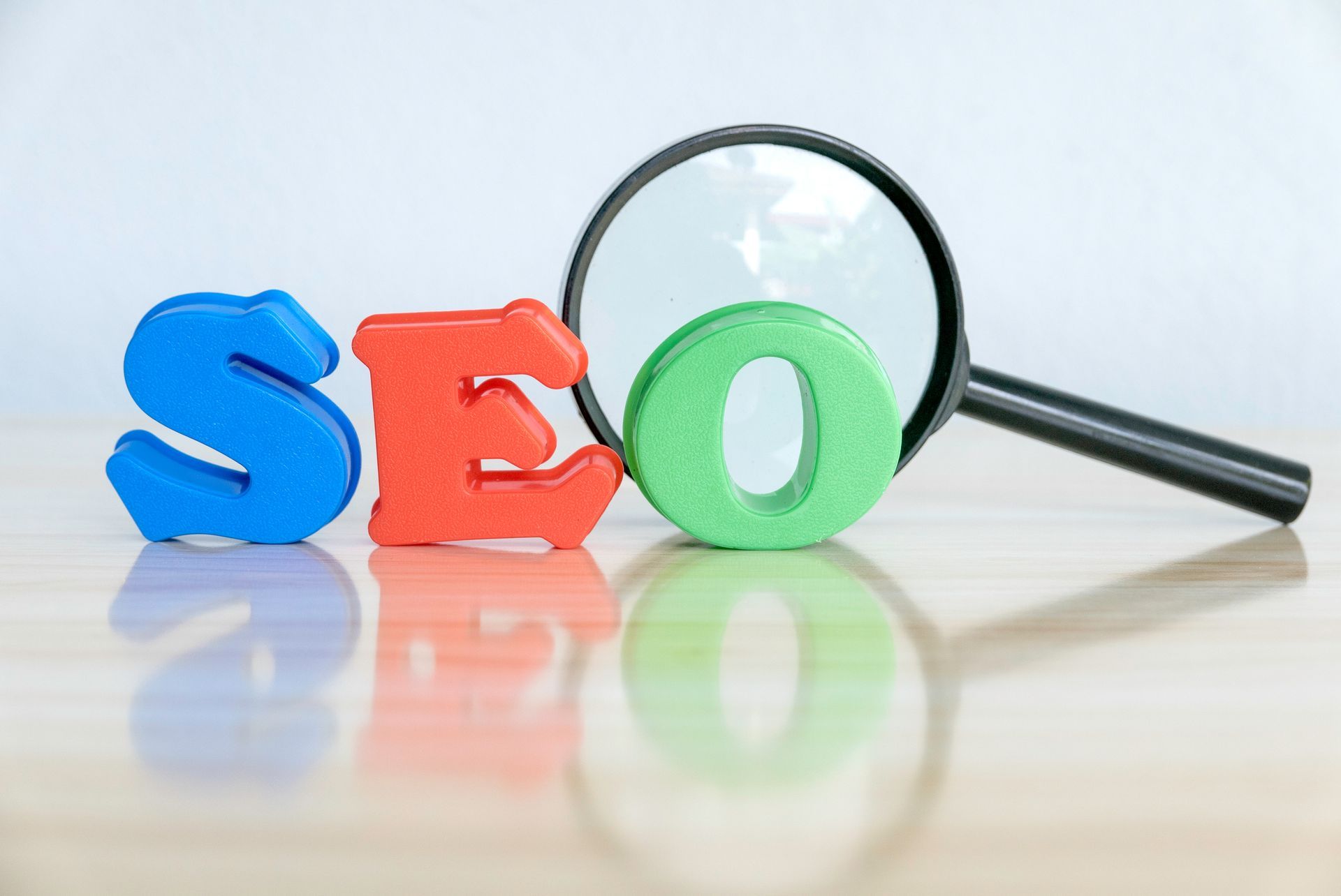 SEO letters (blue, red, and green) with magnifying glass.
