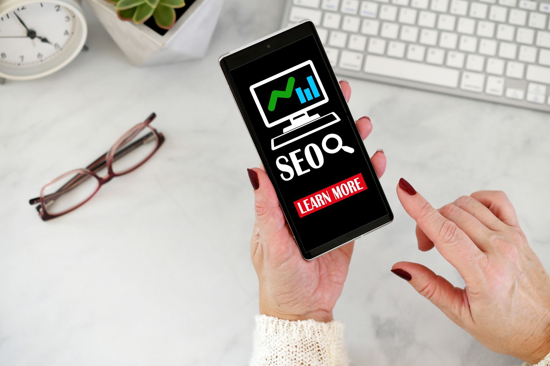 Person holding smartphonPerson holding smartphone with “SEO” graphic, showing a graph and “Learn Mor