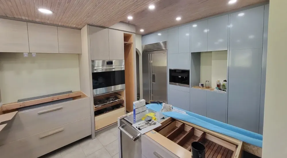 A kitchen with stainless steel appliances and wooden cabinets is being remodeled.