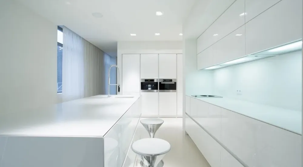 A kitchen with all white cabinets , counter tops , and stools.