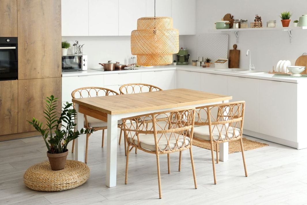 A kitchen with a wooden table and chairs and a potted plant.