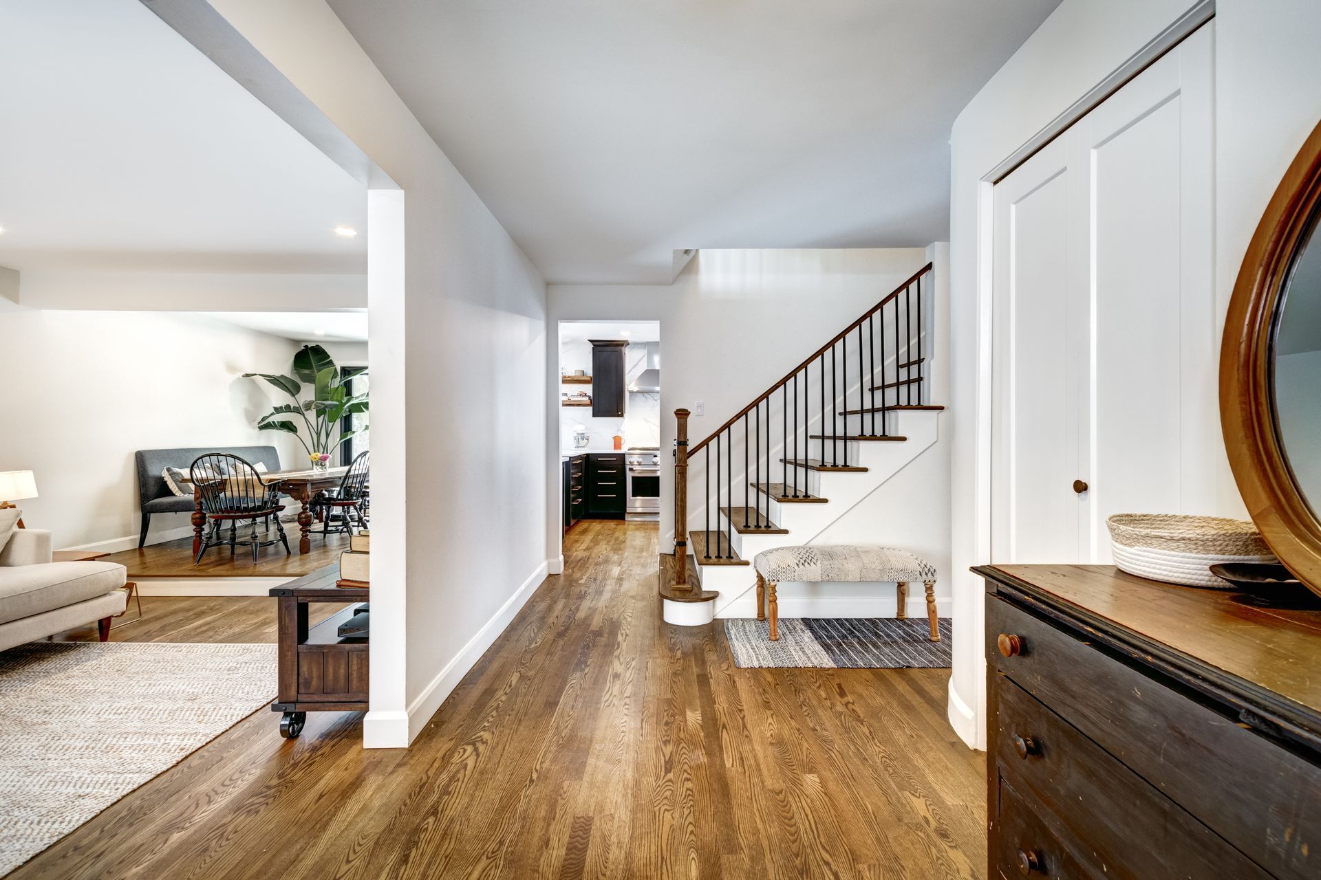 A hallway in a house with hardwood floors and stairs leading up to the second floor.
