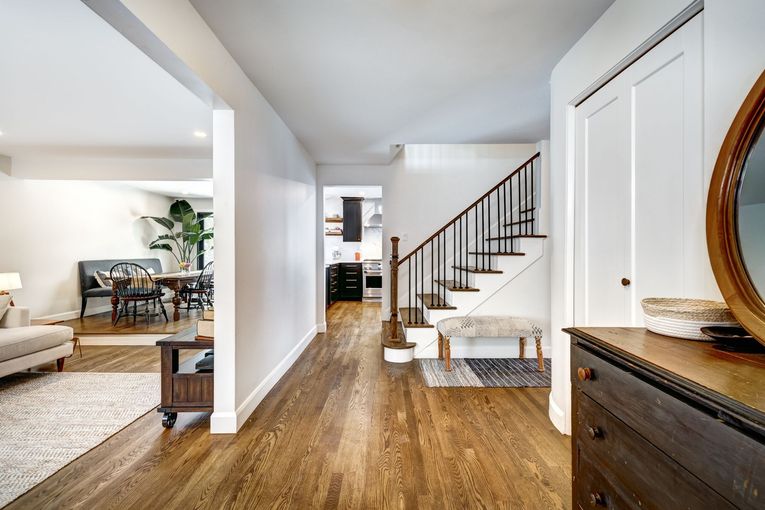 A hallway in a house with hardwood floors and stairs leading up to the second floor.