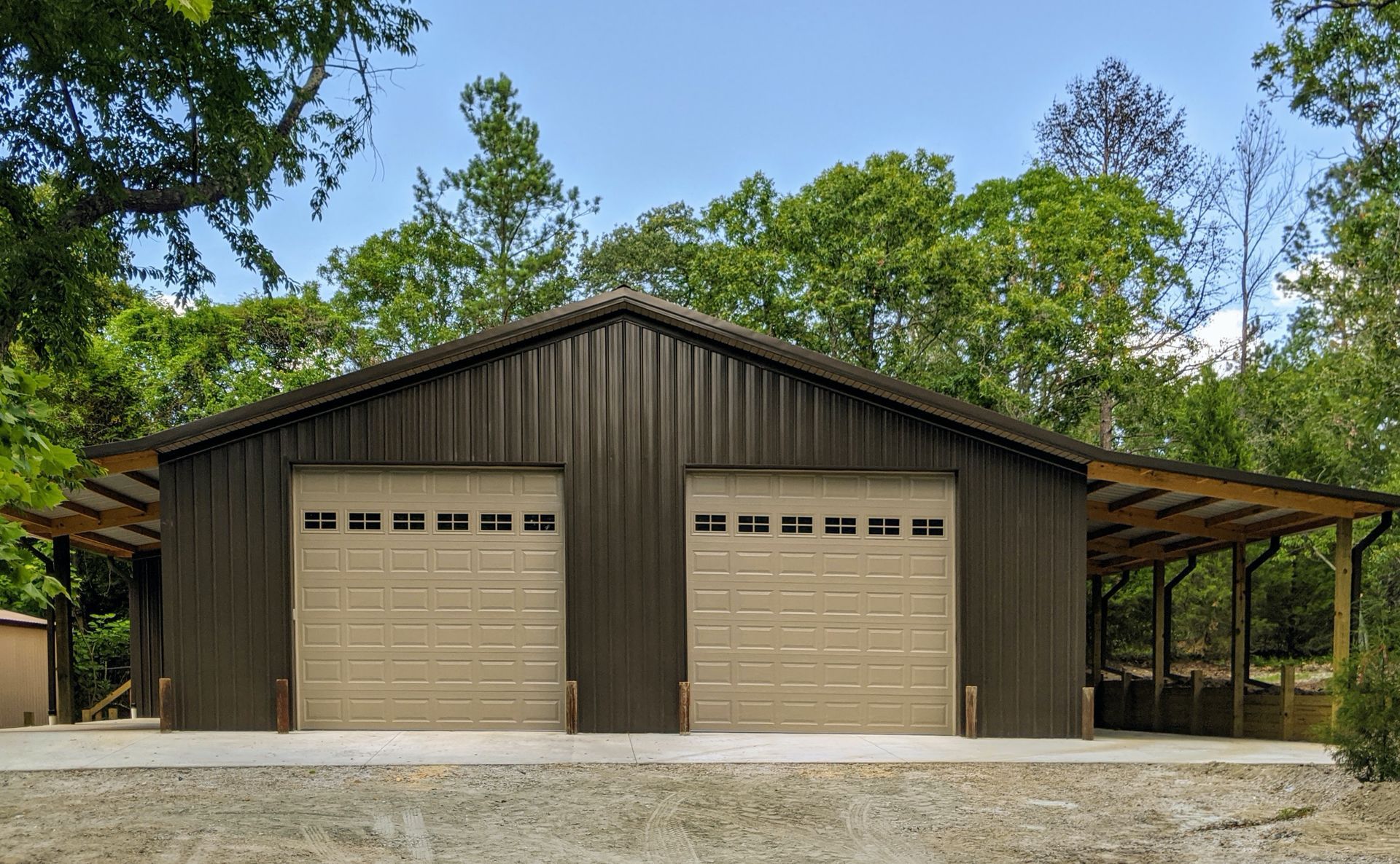 A large metal garage with two garage doors and a porch.