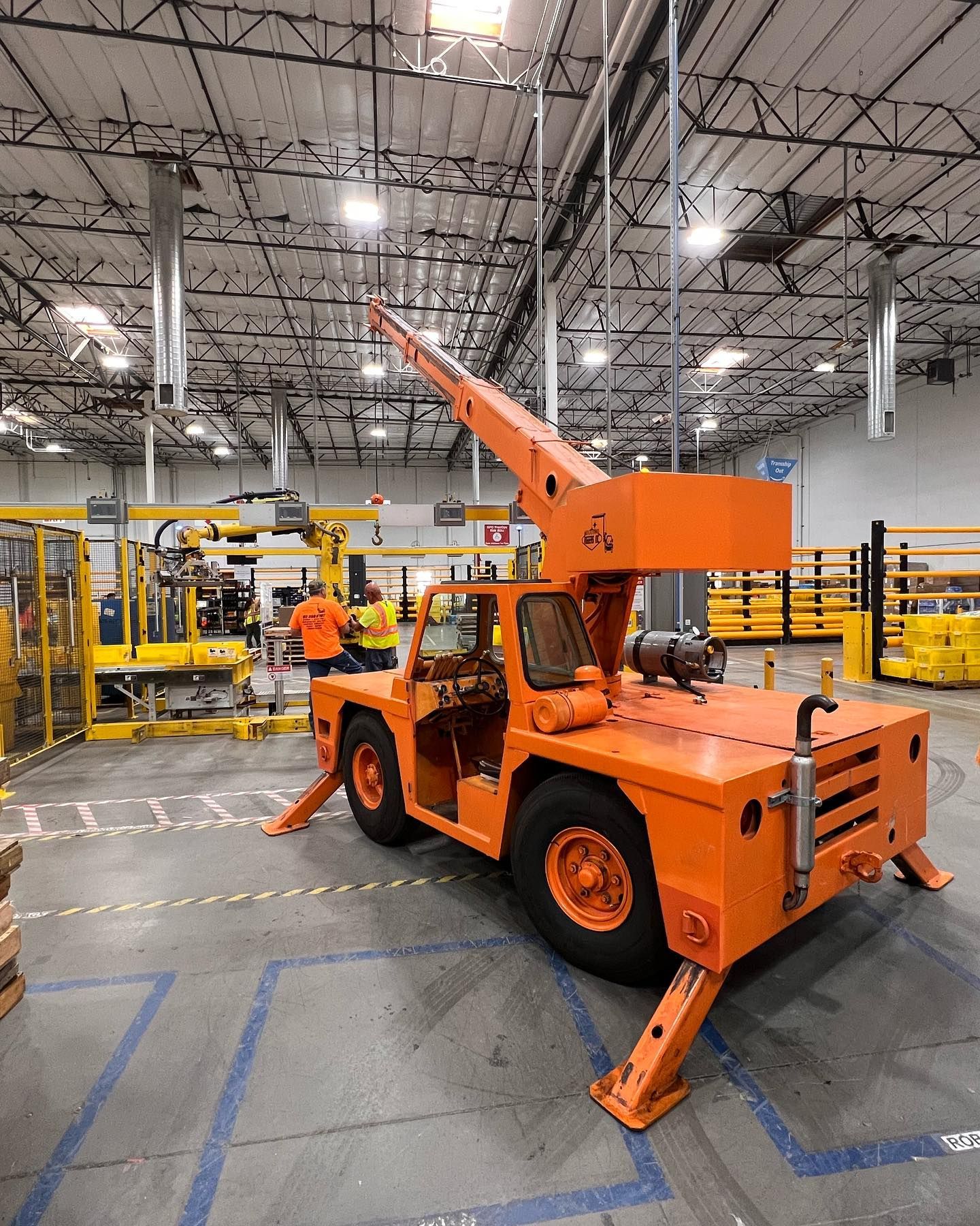 A large orange truck is parked in a large warehouse